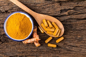 the turmeric powder , capsule and roots curcumin on wooden plate
