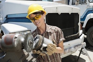 Female industrial worker buffing a truck engine cylinder