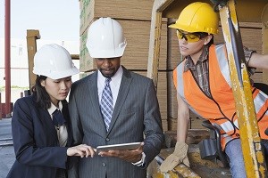 Engineers and female industrial worker looking at tablet PC