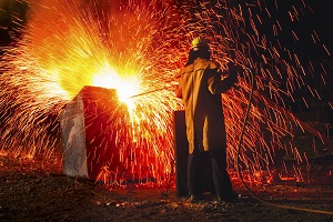 Industrial worker causing shower of sparks, back view