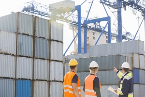 Rear view of workers inspecting cargo containers in shipping yard